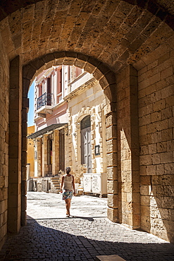 A Woman Walks Through An Arched Walkway, Chania, Crete, Greece