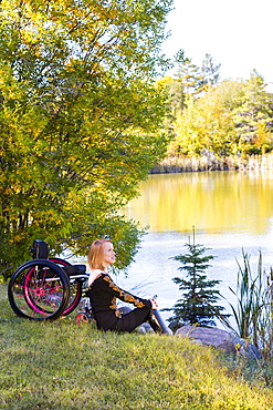 Young Disabled Woman Sitting Beside Her Wheelchair In A City Park In Autumn, Edmonton, Alberta, Canada