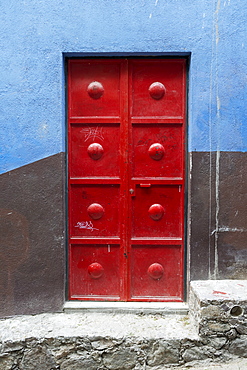 Red Metal Door On A Wall Painted Brown And Blue, San Miguel De Allende, Guanajuato, Mexico