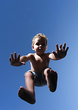 Low Angle View Of A Child In Mid-Air Against A Blue Sky, Tarifa, Cadiz, Andalusia, Spain