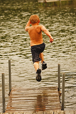 Boy Running And Jumping Off The Dock In A Lake