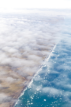 Aerial View Of The North Slope Coastline Shrouded In A Thin Layer Of Clouds, Icebergs Floating In The Arctic Ocean, Deadhorse, Alaska, United States Of America