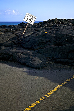 Speed Limit Sign Bending To The Side In The Black Lava Rock On The Coast, Hawaii, United States Of America