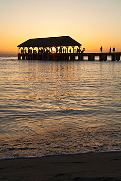 Sunset over ocean and silhouette of tourists on Hanalei Pier, Hanalei Bay, Hanalei, Kauai, Hawaii, United States of America