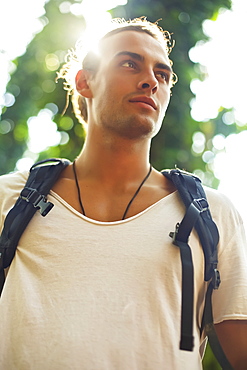 Low angle view of a young man wearing a backpack with the sun behind him, Hawaii, United States of America