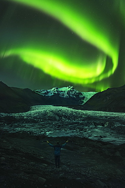 Person Standing With Their Arms Raised As If Orchestrating The Northern Lights, Iceland