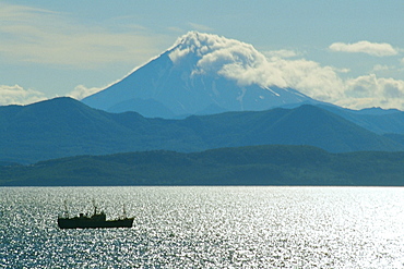 Boat in the river with a volcano in the background, Viluchinsky Volcano, Bay of Petropavlovsk, Kamchatka, Russia