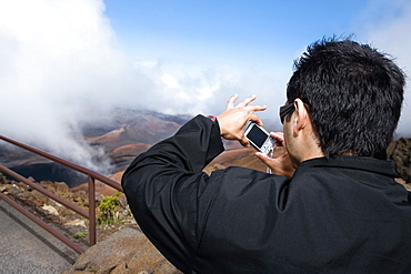 Rear view of a young man taking a photograph, Haleakala National Park, Maui, Hawaii Islands, USA