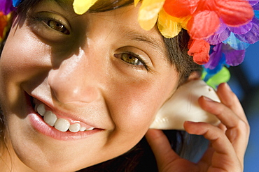 Portrait of a girl wearing flowers and listening to a conch shell