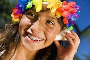 Close-up of a girl listening to a conch shell and smiling