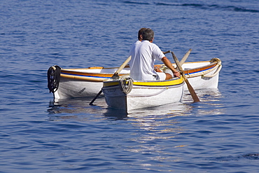 Rear view of two men sitting in boats, Capri, Campania, Italy