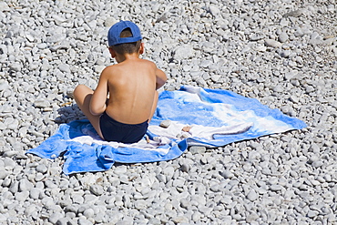 Rear view of a boy sitting on a blanket, Capri, Campania, Italy