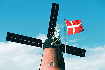 Low angle view of a windmill and the Danish flag, Funen County, Denmark