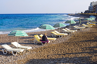 Beach umbrellas and lounge chairs on the beach, Lindos, Rhodes, Dodecanese Islands, Greece