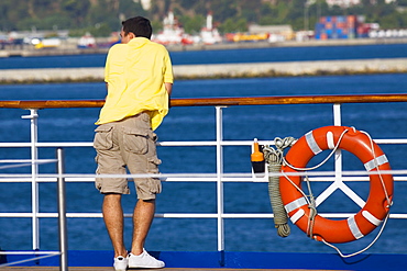 Rear view of a man leaning against a railing