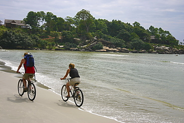 Rear view of a couple riding bicycles on the beach, Sihanoukville, Cambodia