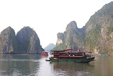 Tourboats in a bay rock formations in the background, Halong Bay, Vietnam