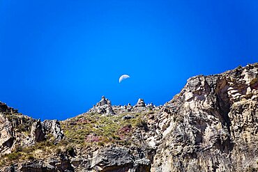 Low angle view of half moon over a rocky mountain, Chivay, Arequipa, Peru