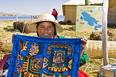 Portrait of a young woman showing a decorated blanket, Peru