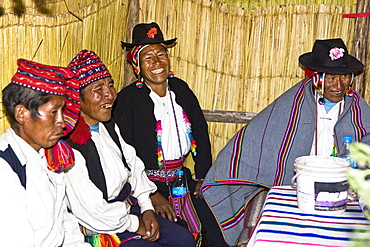 Four people sitting and smiling, Lake Titicaca, Taquile Island, Puno, Peru