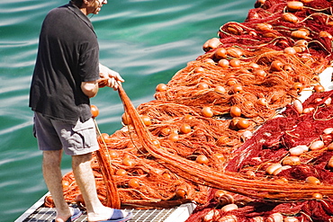 Rear view of a fisherman holding a commercial fishing net, Marina Grande, Capri, Sorrento, Sorrentine Peninsula, Naples Province, Campania, Italy