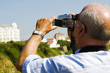 Rear view of a man filming with his home video camera, Biarritz, Basque Country, Pyrenees-Atlantiques, Aquitaine, France