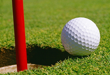 Close-up of a golf ball at the edge of hole