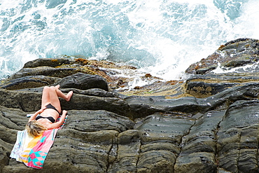 High angle view of a woman lying on cliff, RioMaggiore, Cinque Terre, Italian Riviera, Cinque Terre National Park, Vernazza, La Spezia, Liguria, Italy