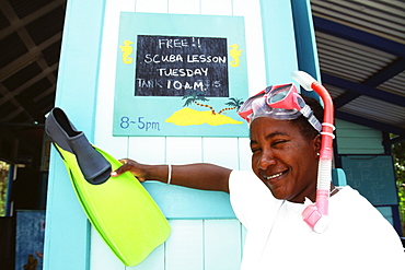 A lady poses in front of a notice while holding a flipper, Port Elizabeth