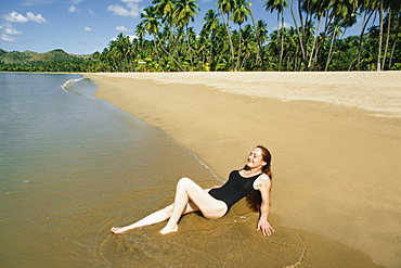 Side view of a woman relaxing on a beach, Mayaquez beach,San Juan, Puerto Rico