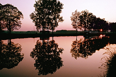 Silhouetted trees being reflected in the Bungundy Canal, France