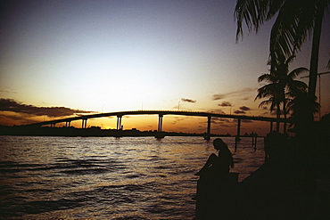 Tranquil seascape and a bridge silhouetted against the sky at sunset, Grand Bahamas, Bahamas