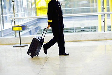 Side profile of a pilot pulling luggage at an airport, Madrid, Spain