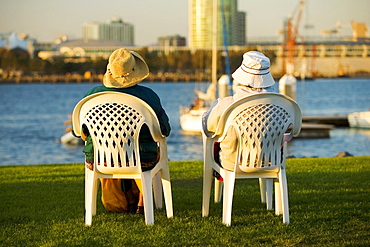 Rear view of two people sitting on a waterfront, San Diego Bay, San Diego, California, USA