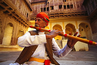 Close-up of a mature man playing a flute in a fort, Meherangarh Fort, Jodhpur, Rajasthan, India