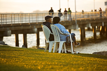 Side profile of two people sitting on a waterfront, San Diego Bay, San Diego, California, USA