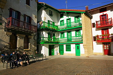 Four people sitting on a bench in a courtyard, Spain