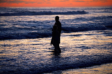 Father and his daughter standing in the water at the beach