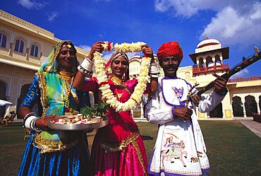 Portrait of a mid adult man with two young women greeting, Jaipur, Rajasthan, India