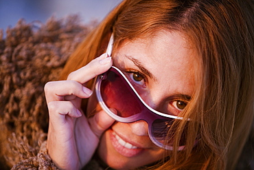 Portrait of a mid adult woman peeking over her sunglasses