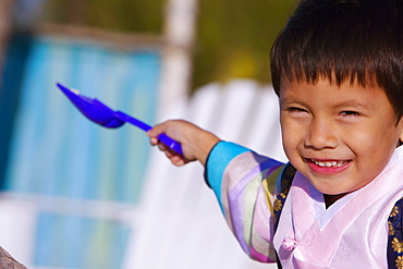 Portrait of a boy in traditional clothing holding a shovel