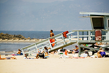 People sitting around a lifeguard stand on the beach