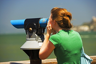 Close-up of woman looking through a hand-held telescope