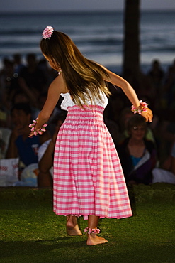 Rear view of a teenage girl hula dancing in a lawn