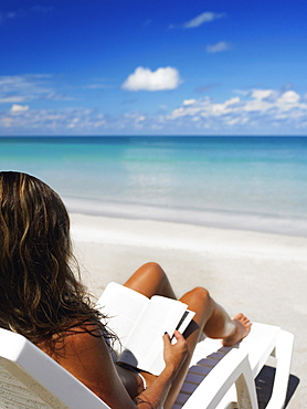 Woman sitting on a lounge chair and reading a book on the beach, Providencia, Providencia y Santa Catalina, San Andres y Providencia Department, Colombia