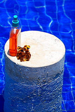 High angle view of an oil bottle and a clutcher on a column in a swimming pool, Cancun, Mexico