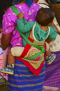 Rear view of a woman carrying her baby on her back, Luang Prabang, Laos