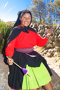 Portrait of a young woman spinning a reel of thread, Taquile Island, Lake Titicaca, Puno, Peru