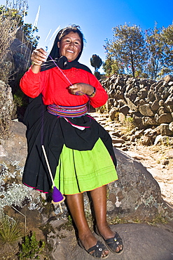 Portrait of a young woman spinning a reel of thread, Taquile Island, Lake Titicaca, Puno, Peru