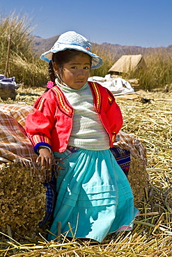 Portrait of a girl leaning against a bale of straw